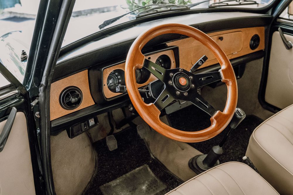 Interior detail shots of a classic car dashboard showing wooden steering wheel and beige upholstery from multiple angles.