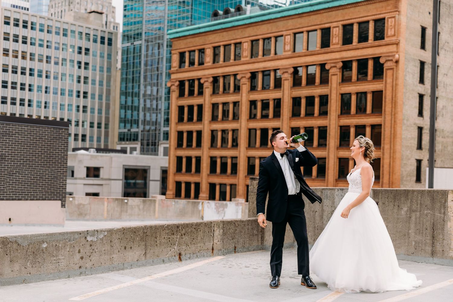 A wedding couple poses together in front of historic brick buildings in an urban setting.