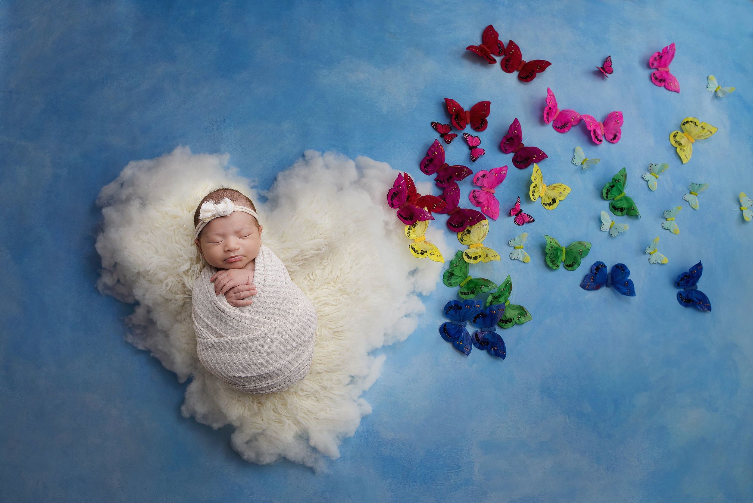 Creative newborn photography composite with baby posed on cloud and rainbow butterflies photographed by Valerie Kay Photography in Austin