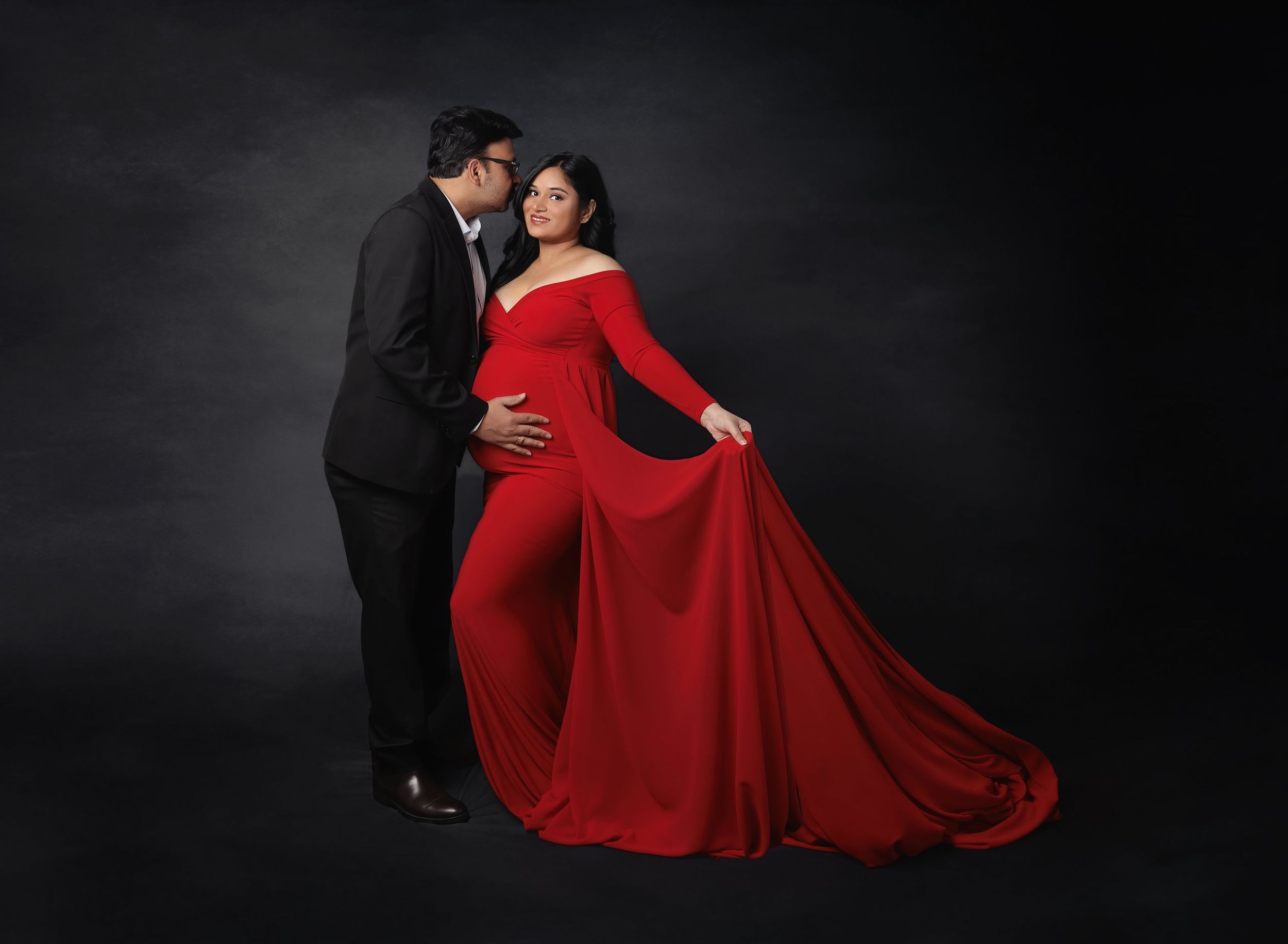 Elegant studio maternity portrait of expecting couple with flowing red gown photographed by Valerie Kay Photography in Austin