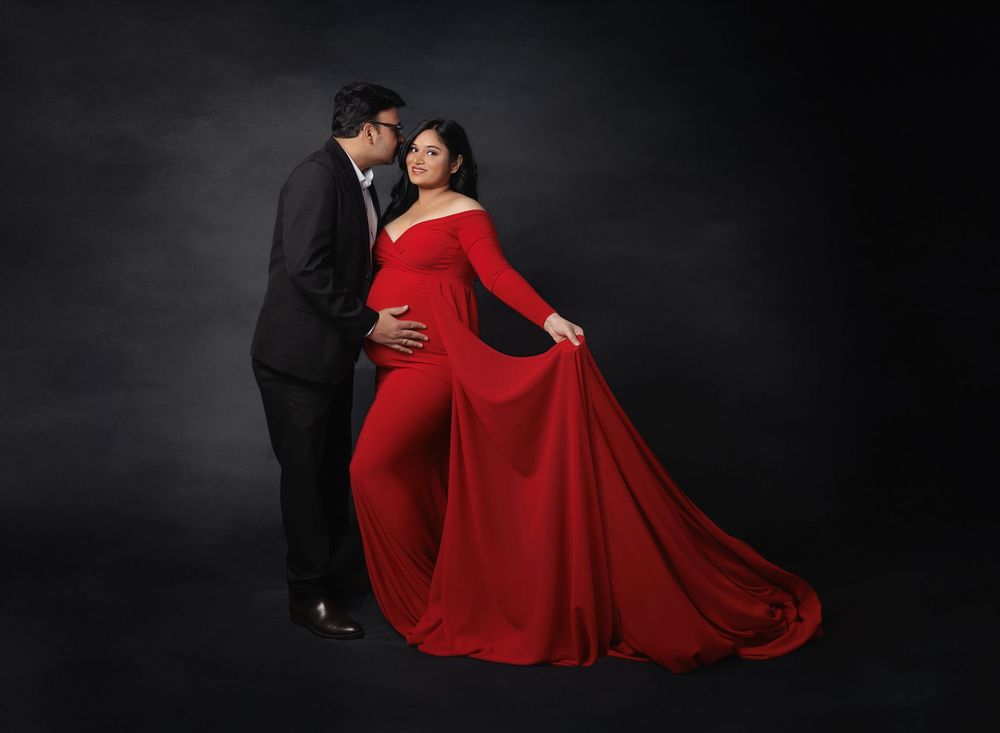 Elegant studio maternity portrait of expecting couple with flowing red gown photographed by Valerie Kay Photography in Austin