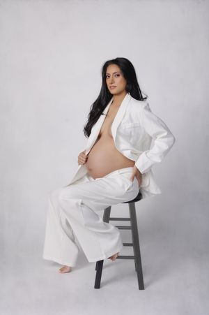 Studio maternity photography portrait of expecting mother seated on stool wearing white outfit photographed by Valerie Kay Photography Austi