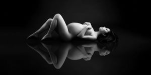 Black and white fine art maternity portrait of expecting mother reclining in studio photographed by Valerie Kay Photography Austin