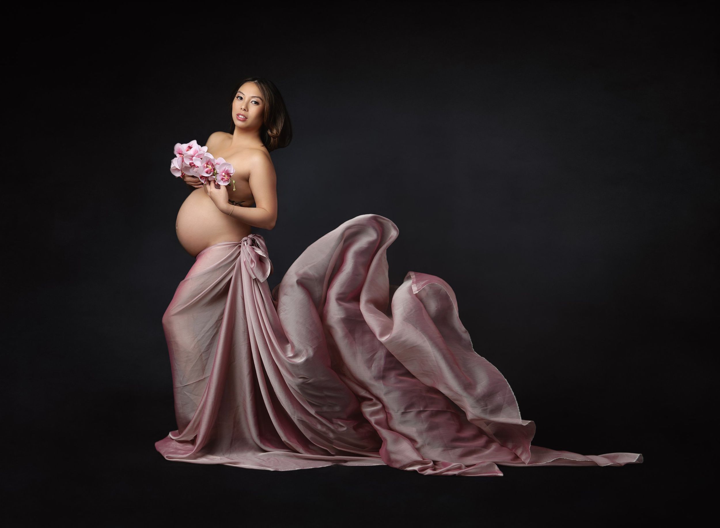 Studio maternity photography portrait of expecting mother wearing flowing pink gown photographed by Valerie Kay Photography in Austin