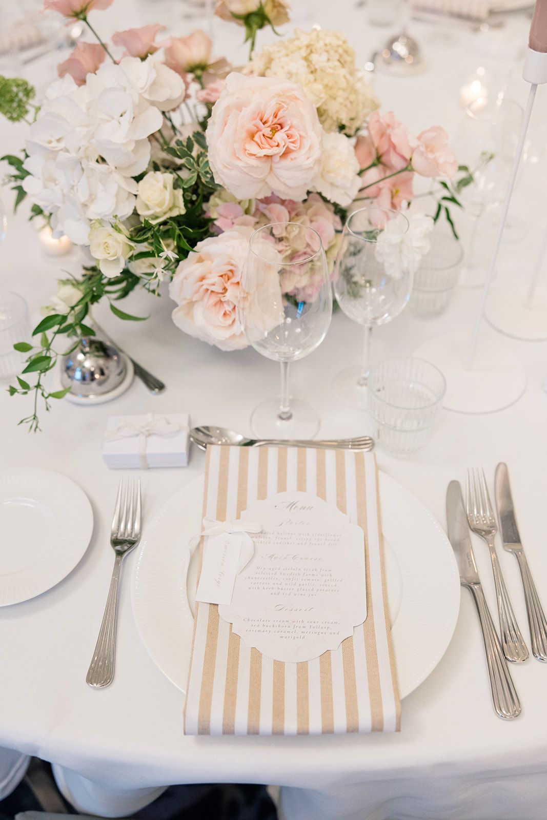 Elegant floral arrangement with white hydrangeas, pink roses and lit candles on a patterned surface creates romantic ambiance.