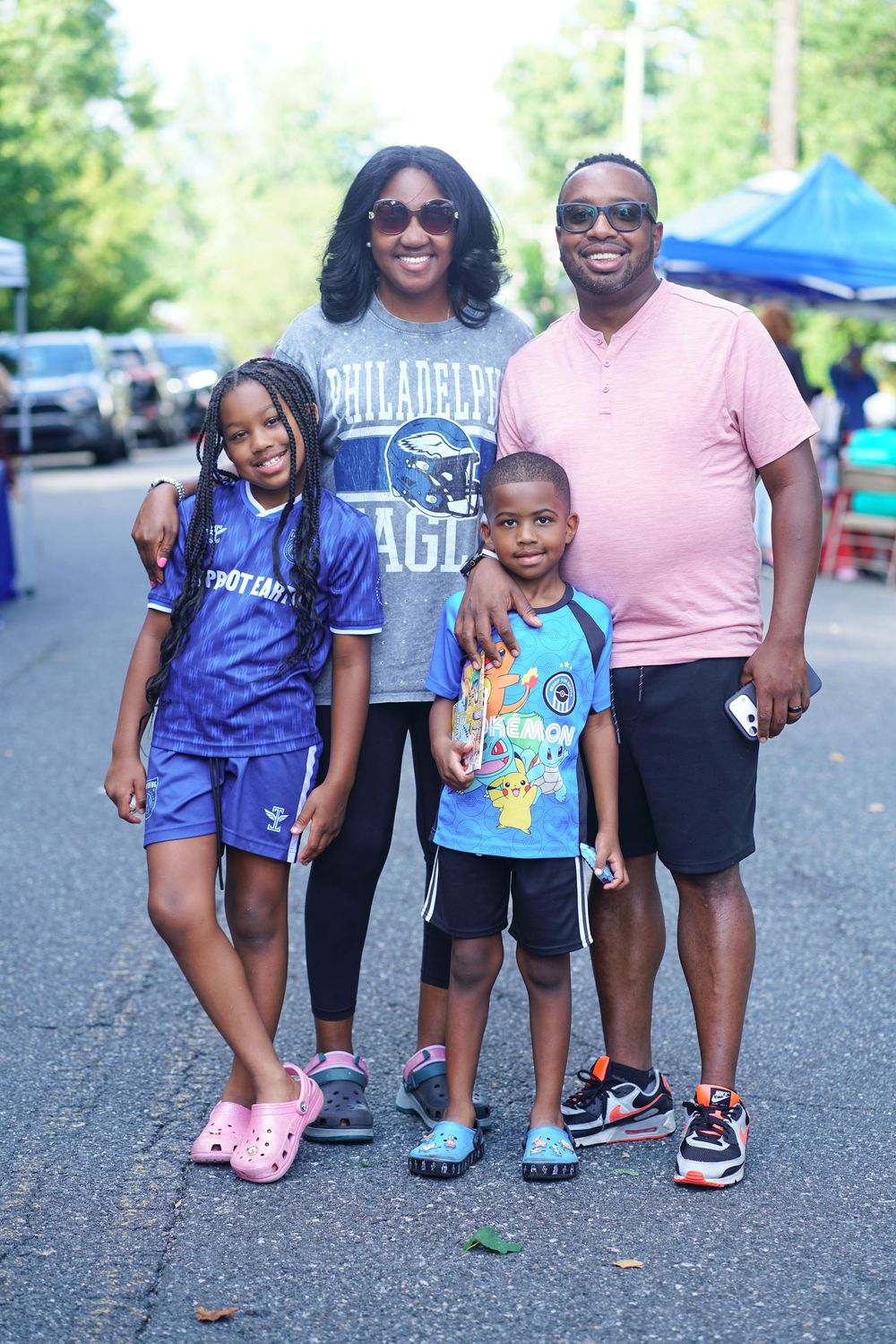 A smiling family of four poses together outdoors, with mom wearing a Philadelphia Eagles jersey.