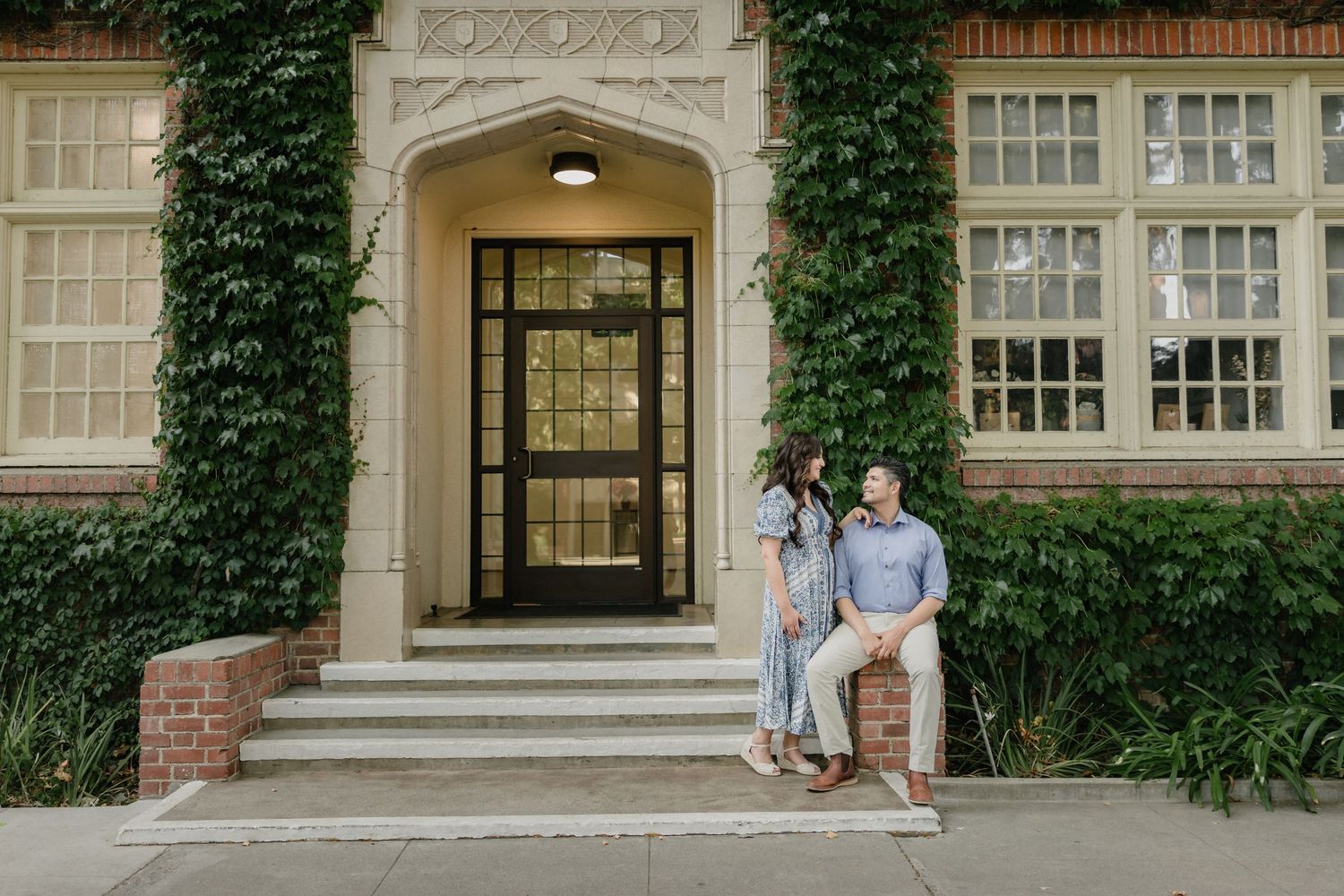 Long white lace wedding dress train trailing on wooden deck in warm sunlight beside rustic barrel planters in Old Sacramento.