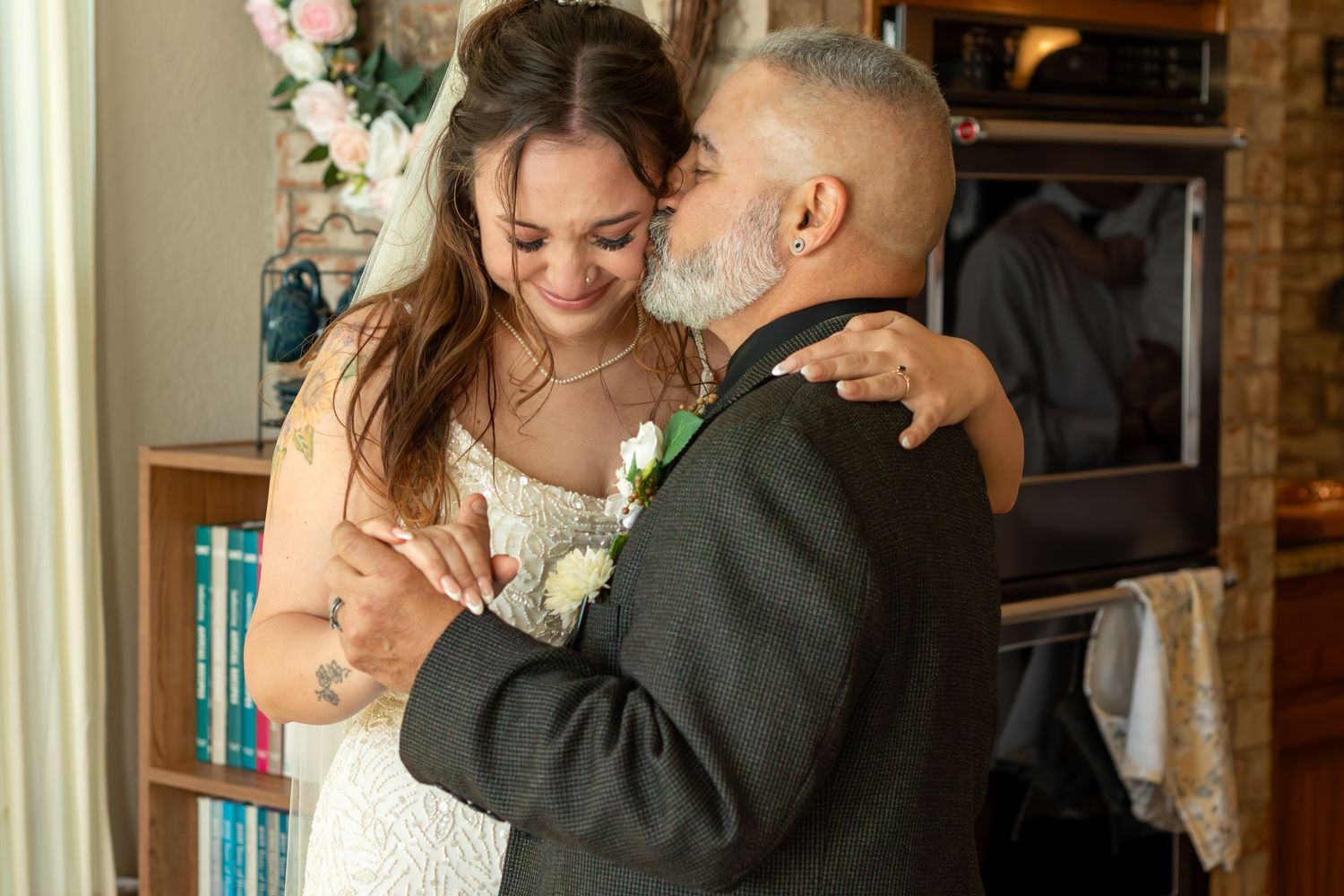 Bride and groom share a tender embrace, smiling together on their wedding day indoors.