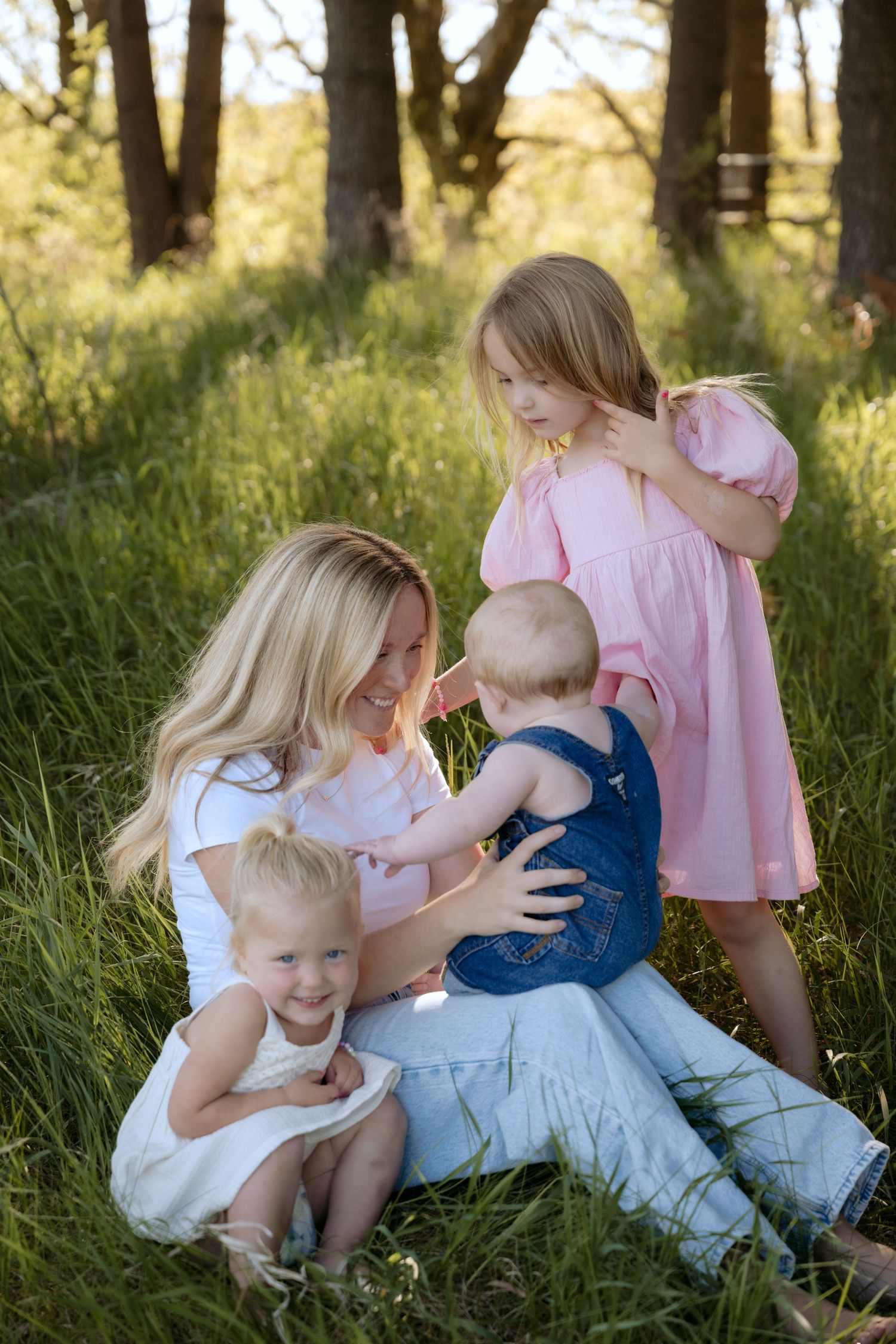 Mom and three toddlers smiling at each other for candid lifestyle outdoor spring session in hudson, WI