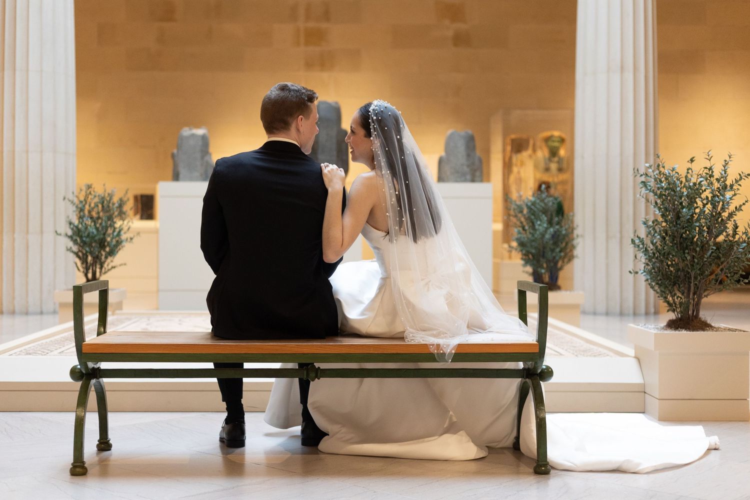 Newlywed couple in wedding attire admiring a Renaissance tondo painting of Madonna and Child in a museum.