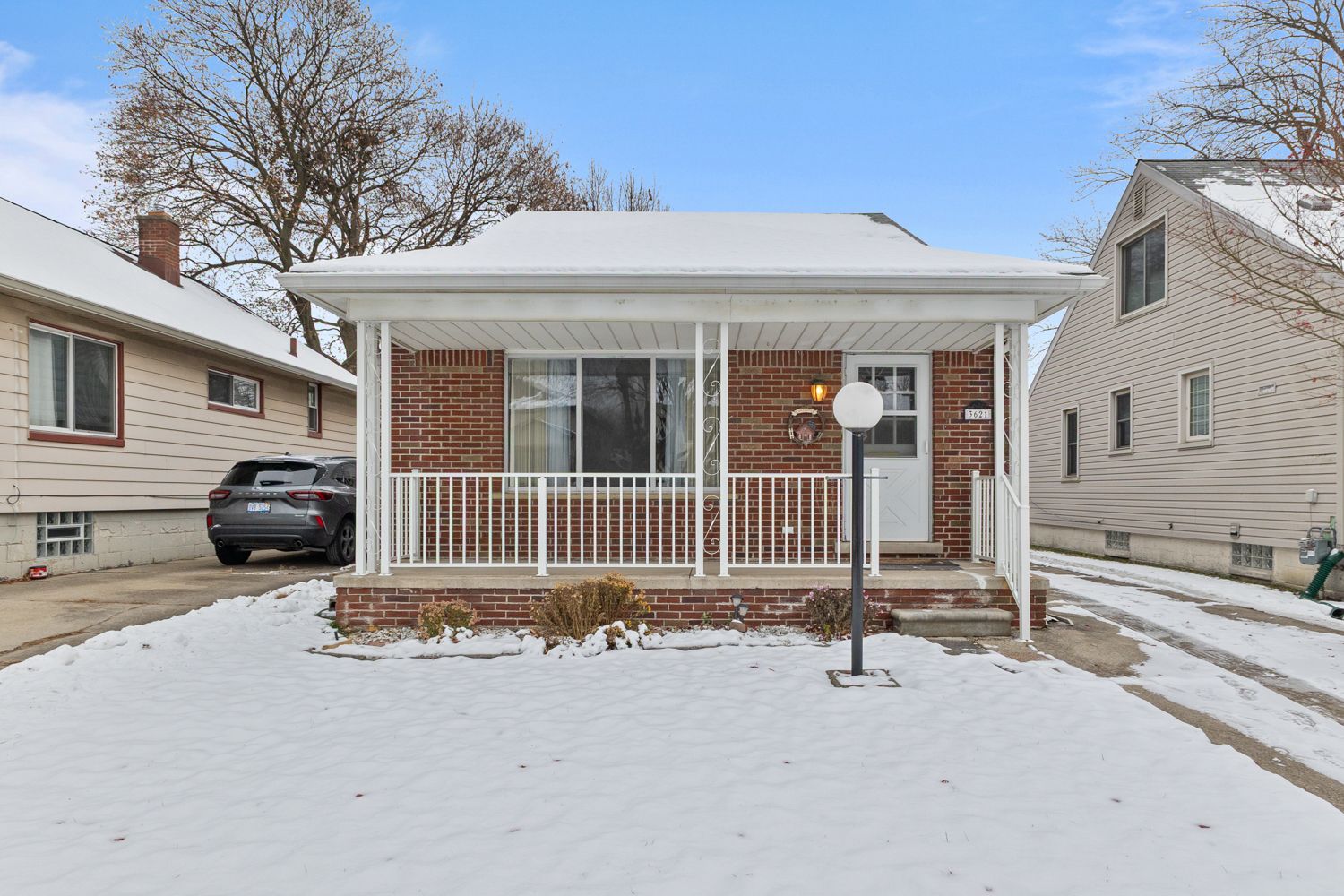 Charming white bungalow with covered front porch, brick accents, and well-maintained lawn.