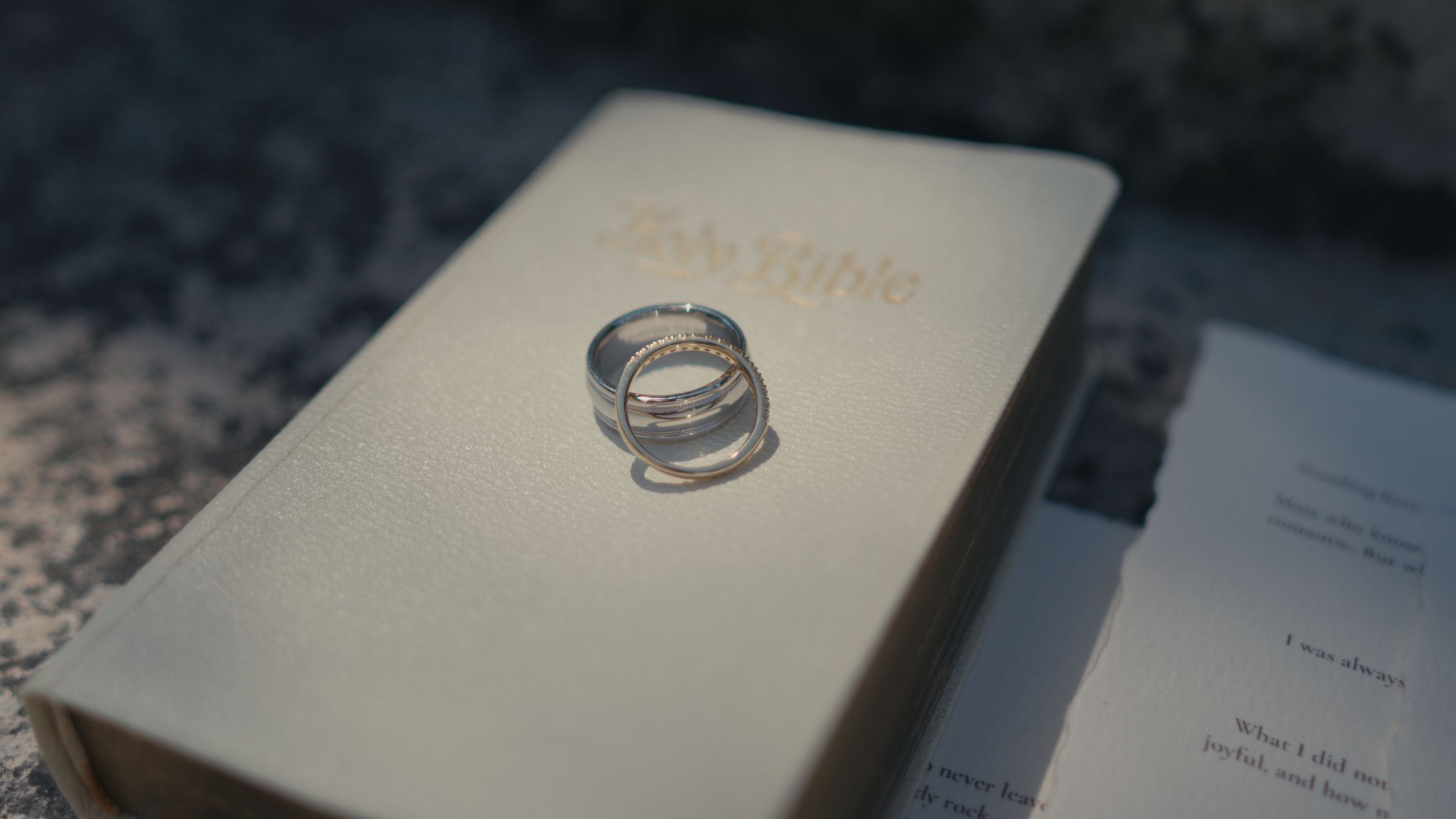 Two silver wedding rings resting on a white Bible, symbolizing marriage and faith.