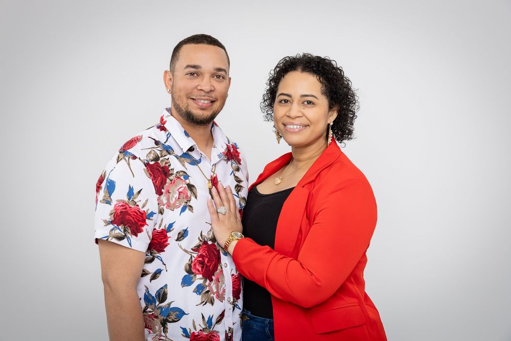 Casual studio portrait with floral shirt and red cardigan against light grey background.