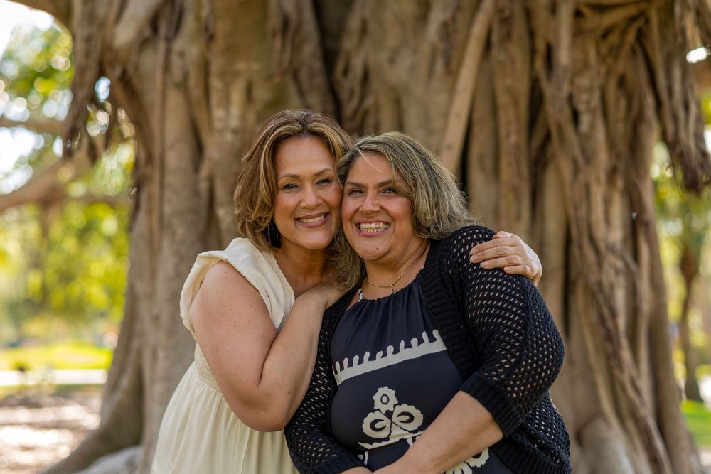 Two people share an intimate moment of laughter under a majestic banyan tree.