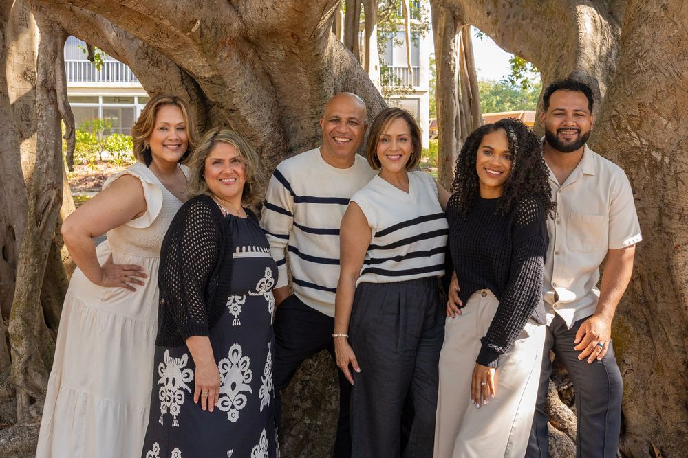 Group photo of family members standing together under a large banyan tree wearing coordinated outfits.