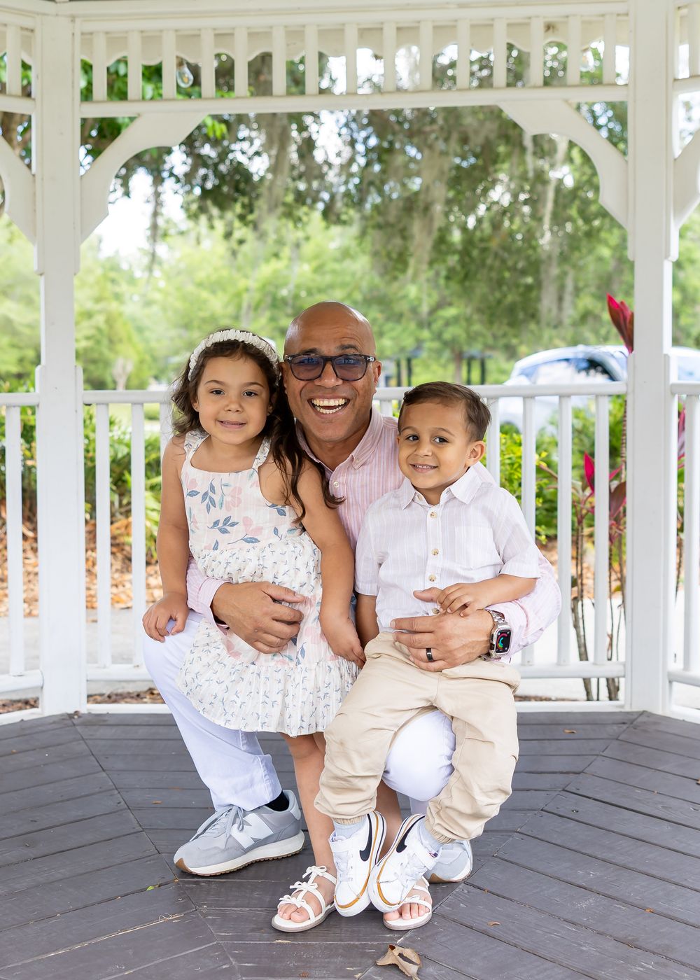 Family members pose together on a white gazebo deck in coordinated casual outfits.