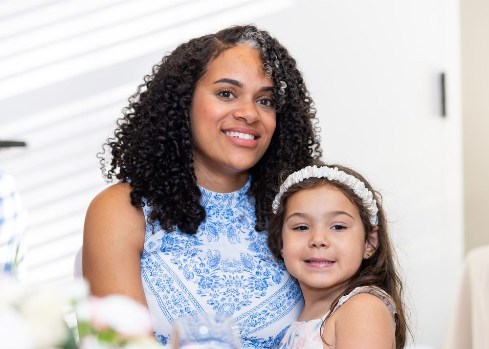Two people in blue attire smile together during an indoor portrait session.
