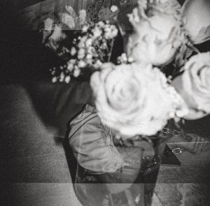 Black and white double exposure photo of roses bouquet with baby's breath flowers and a person's reflection.