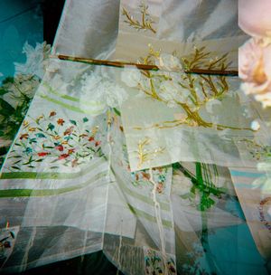 Delicate embroidered white fabric with floral patterns and a decorative branch with white blossoms on display.