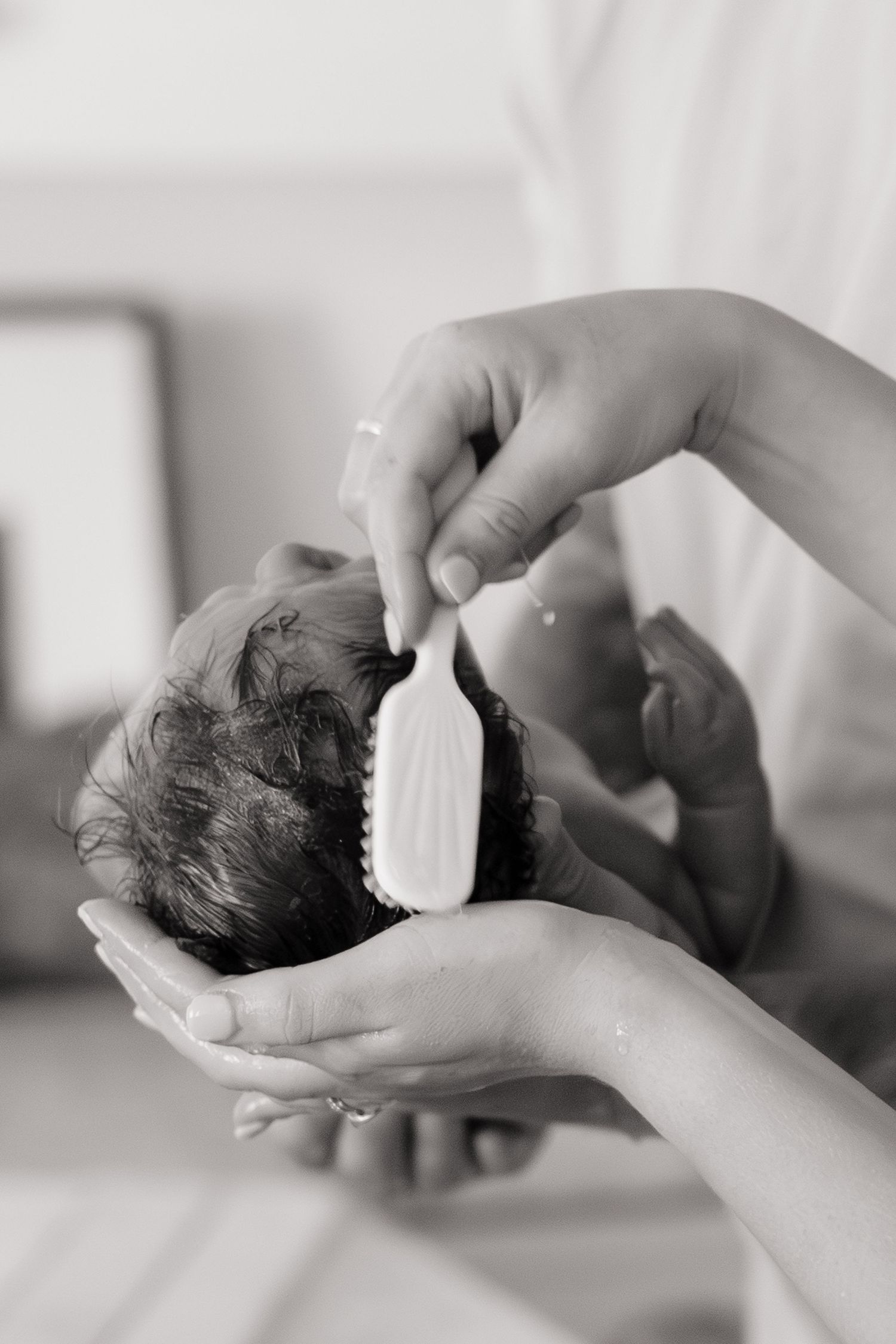 mom brushing newborn baby's wet hair after bath
