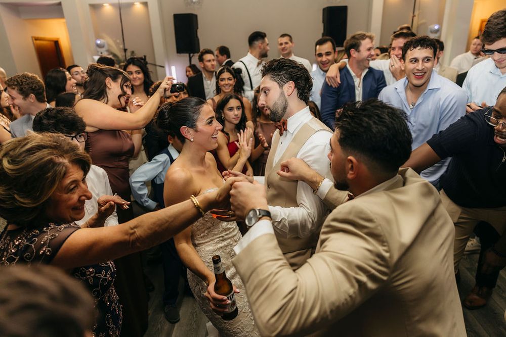 Wedding guests dancing joyfully at a reception party with bride and groom celebrating on the dance floor at Meson Sabika venue in Naperville
