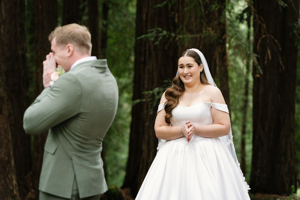 Groom emotional during first look as bride smiles in white gown.