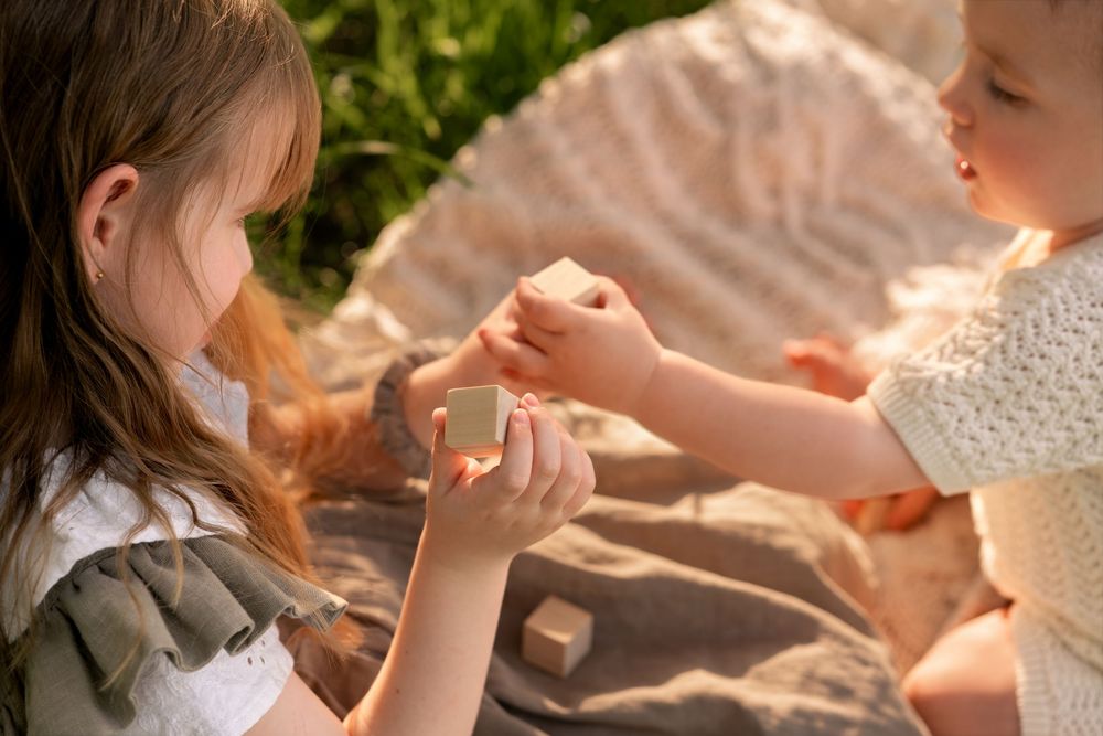 Two young children playing outdoors with small wooden blocks during childhood photoshoot in Lincolnshire.