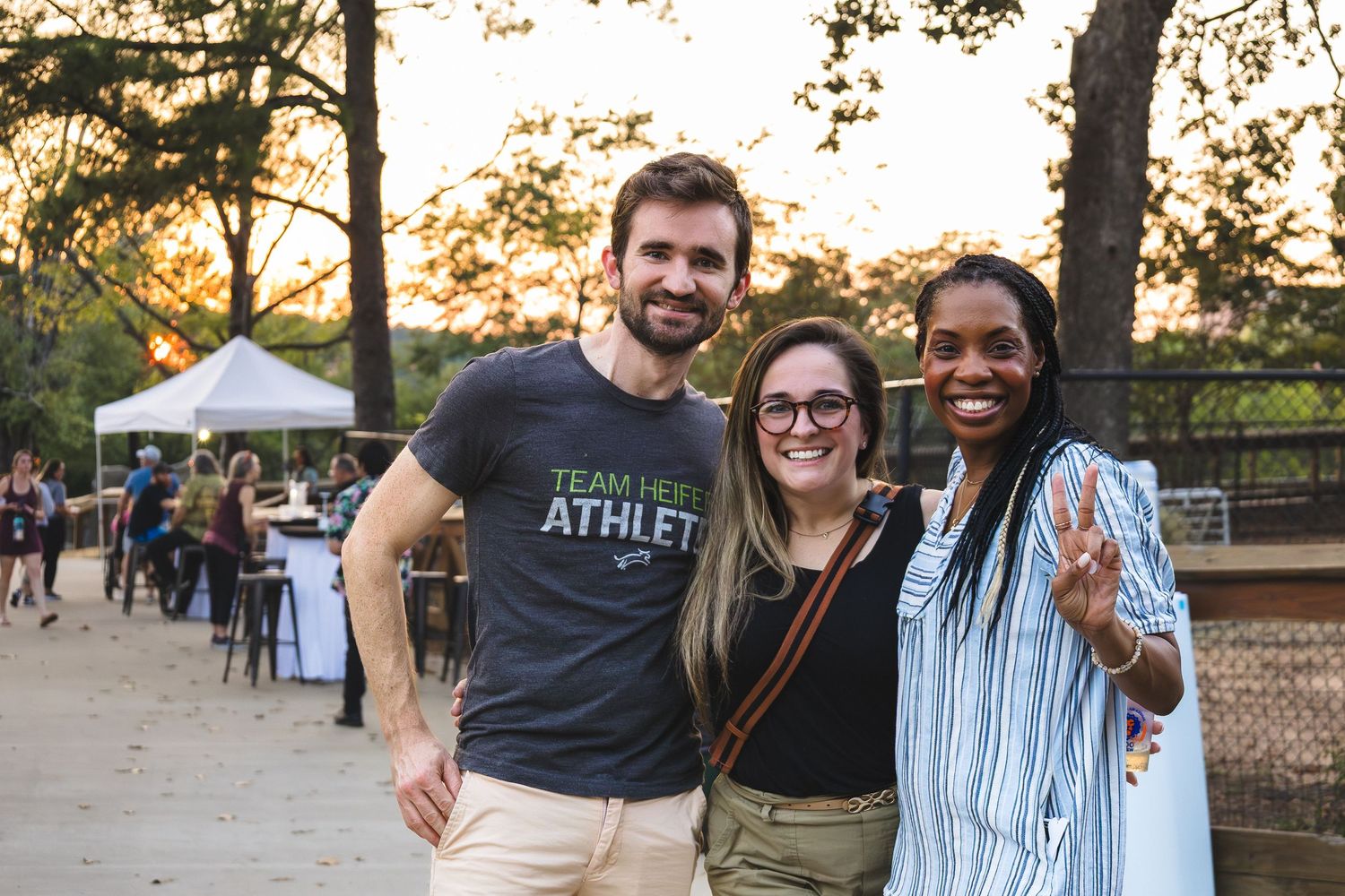 Three friends smiling outdoors at a sunset event, at the Zoo