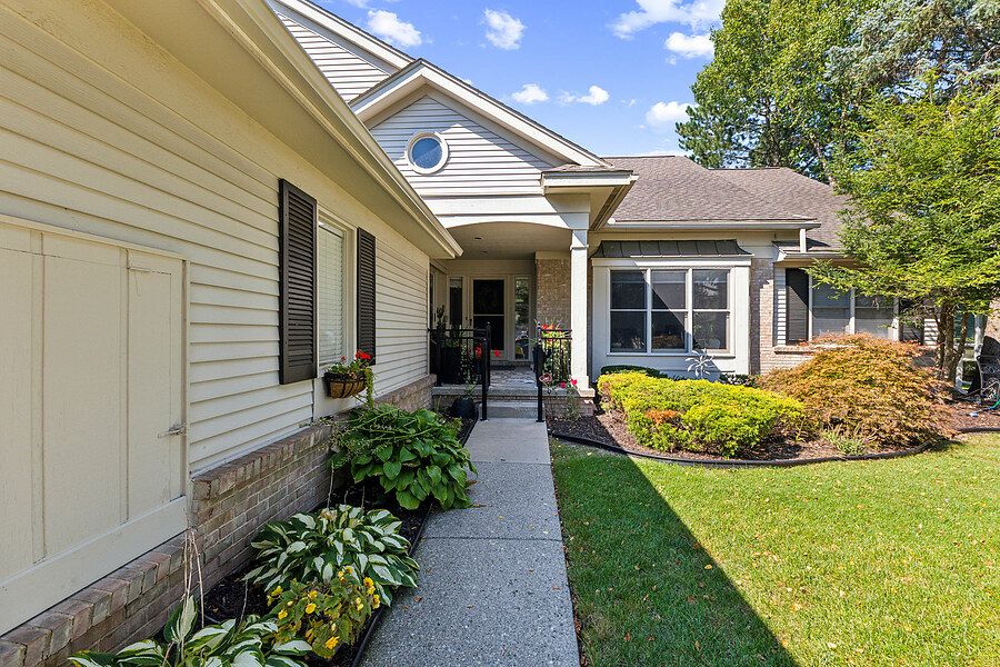 Charming ranch home exterior with manicured landscaping, stone accents, covered porch, and lush green lawn.