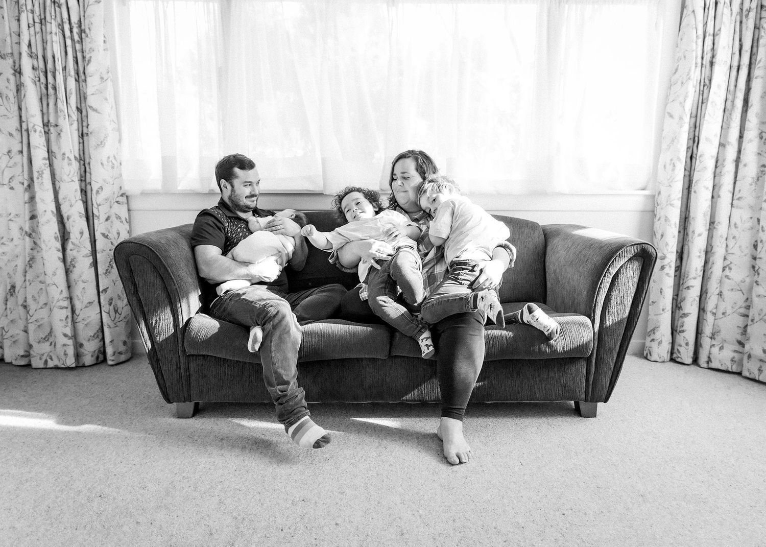 Family cuddling newborn baby during portrait session