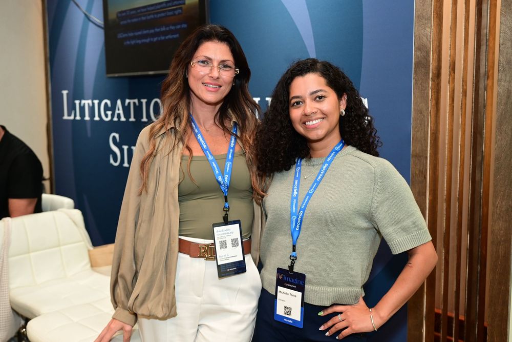 Two professional women wearing conference badges smile together at a Litigation Solutions event.