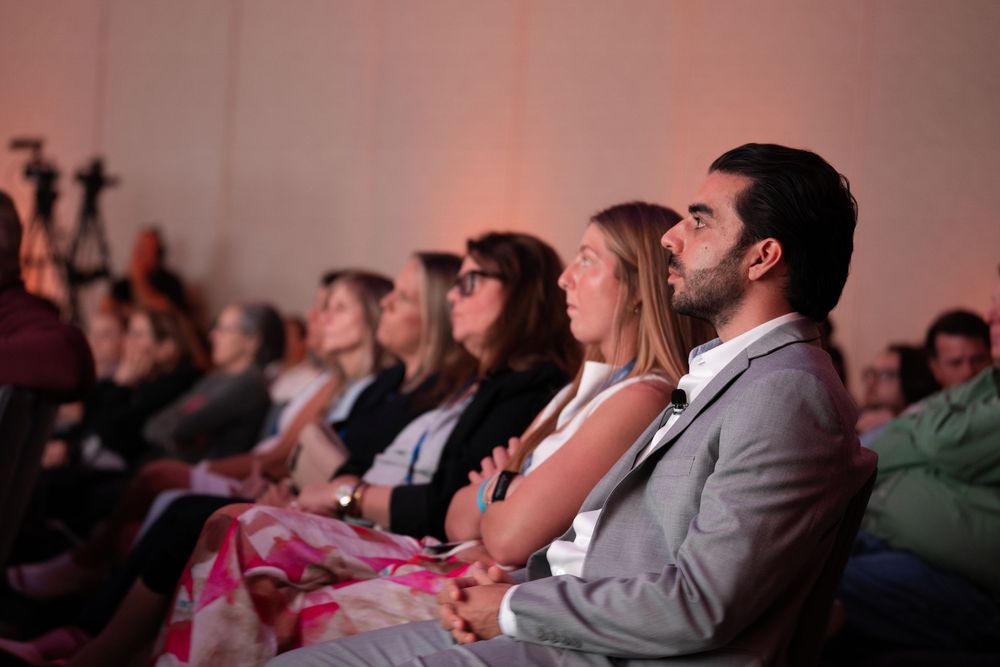 Audience members seated in rows attentively watching a presentation at an indoor event or conference.