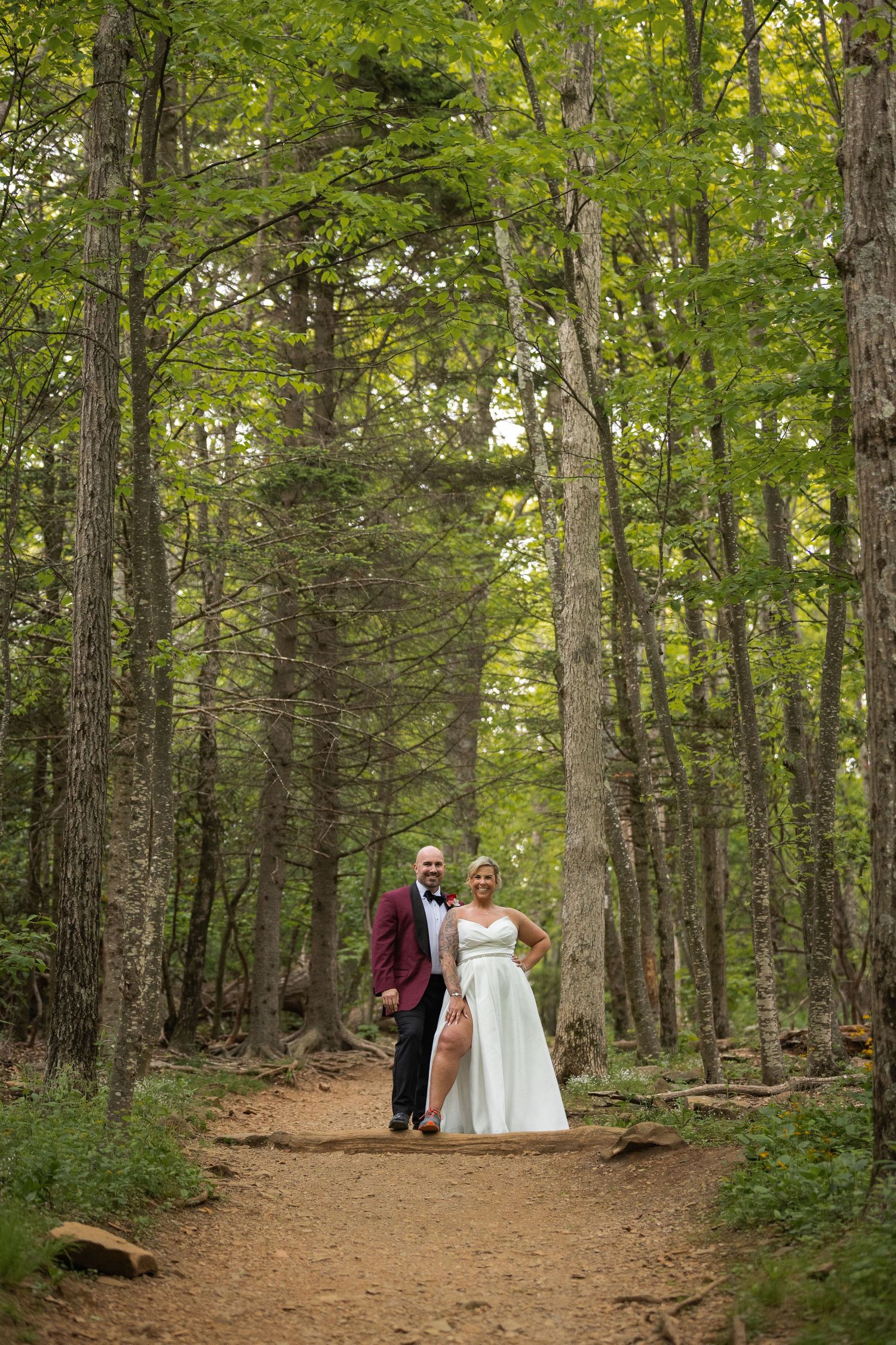 Bride and groom pose hand in hand on a path along Stony Man Summit Trail surrounded by tall green trees during their Shenandoah elopement.
