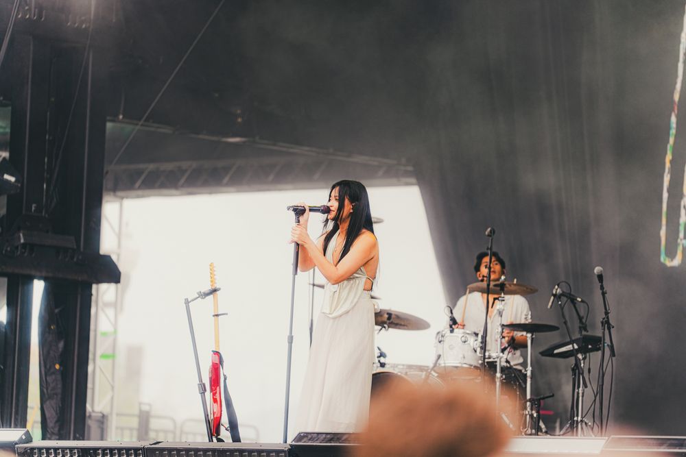 Female vocalist performing on stage at an outdoor music festival.
