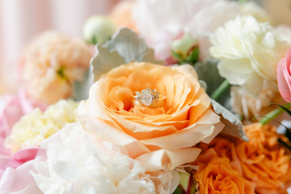 Diamond engagement ring nestled inside a peach garden rose in bridal bouquet.