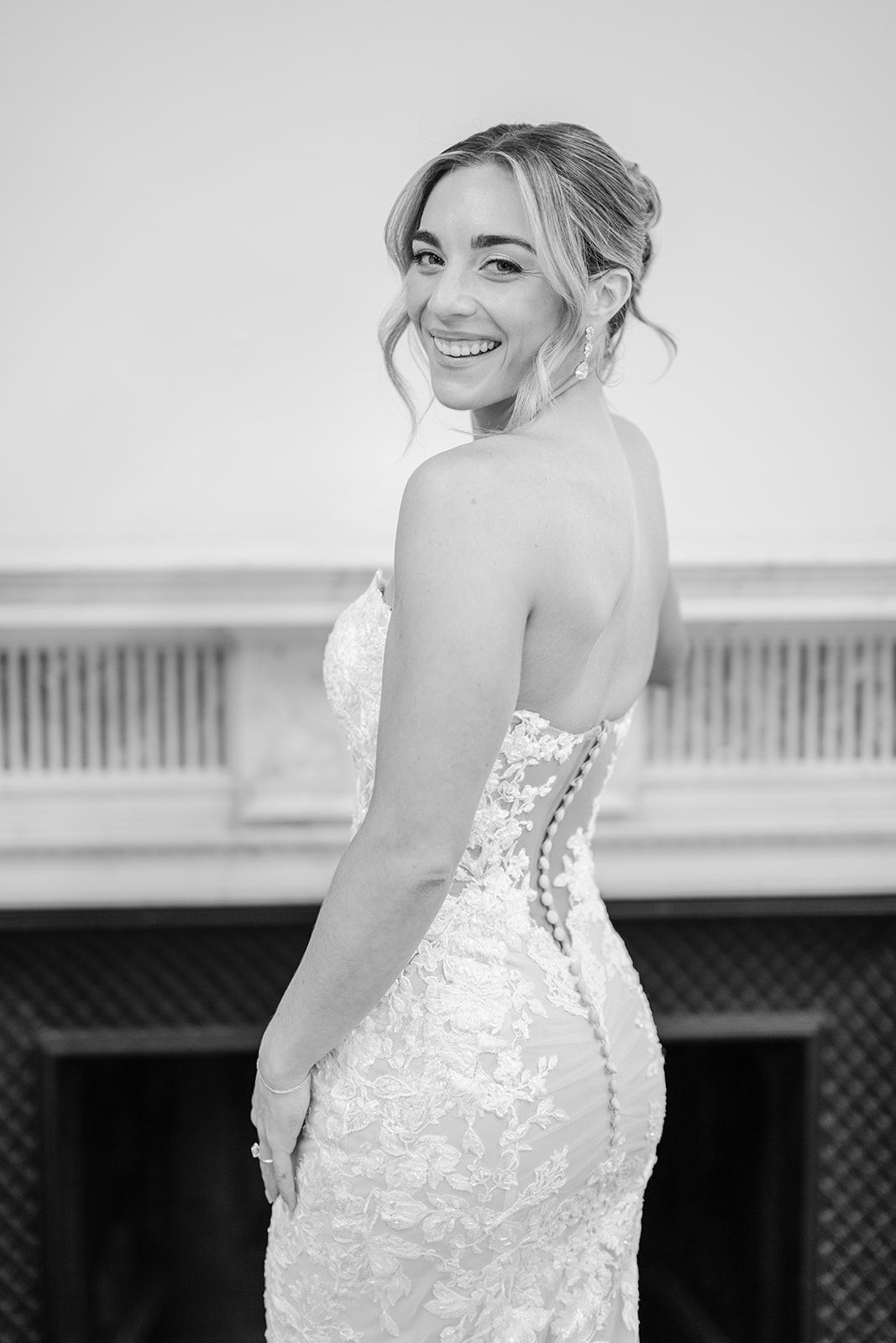 Armour House Wedding - Elegant white lace mermaid wedding dress hanging on a door hanger against a white paneled door.