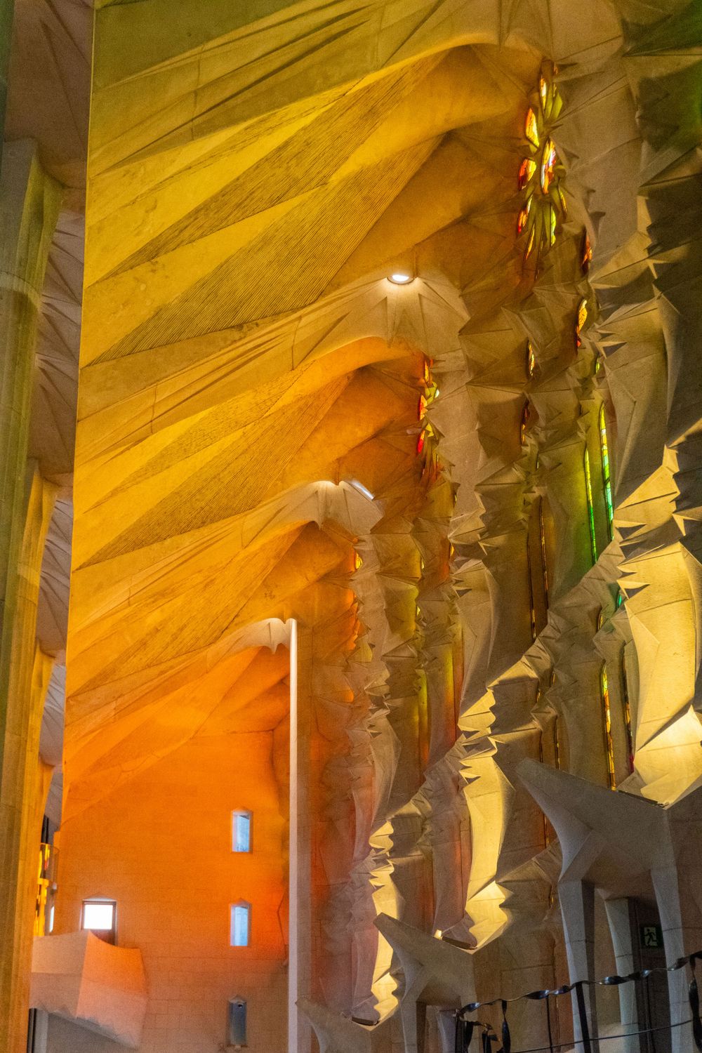 Interior of Sagrada Familia basilica with golden sunlight streaming through stained glass windows.