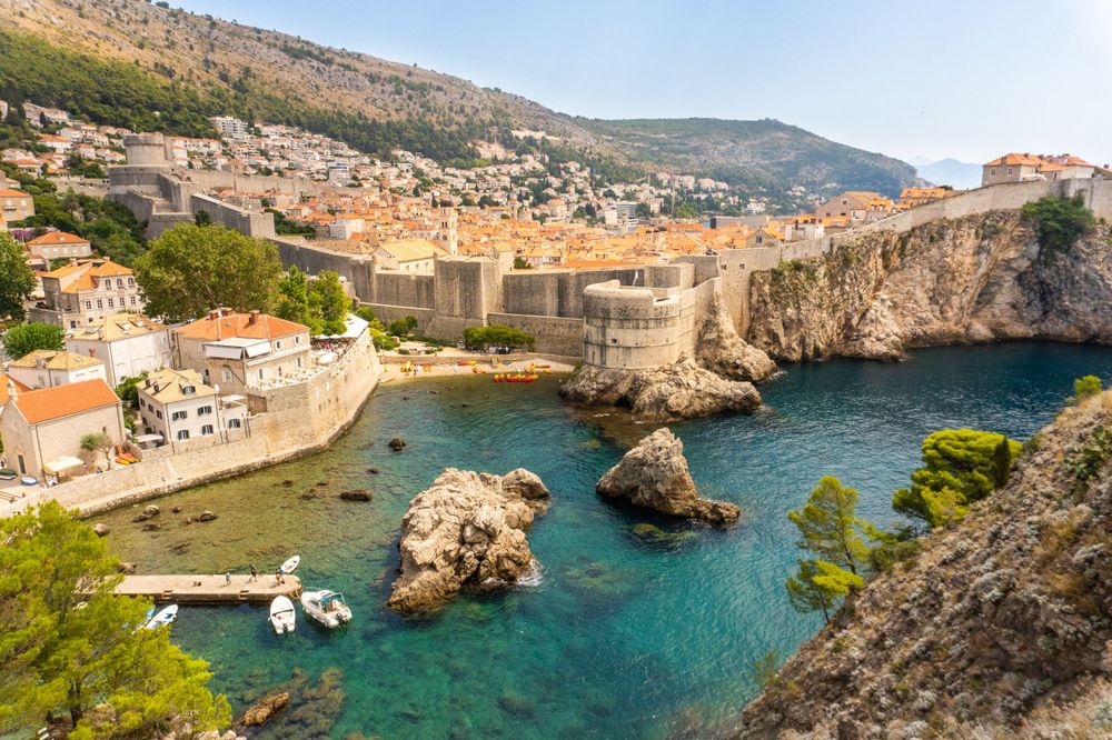 Aerial view of Dubrovnik's old town walls and harbor with crystal clear turquoise waters.