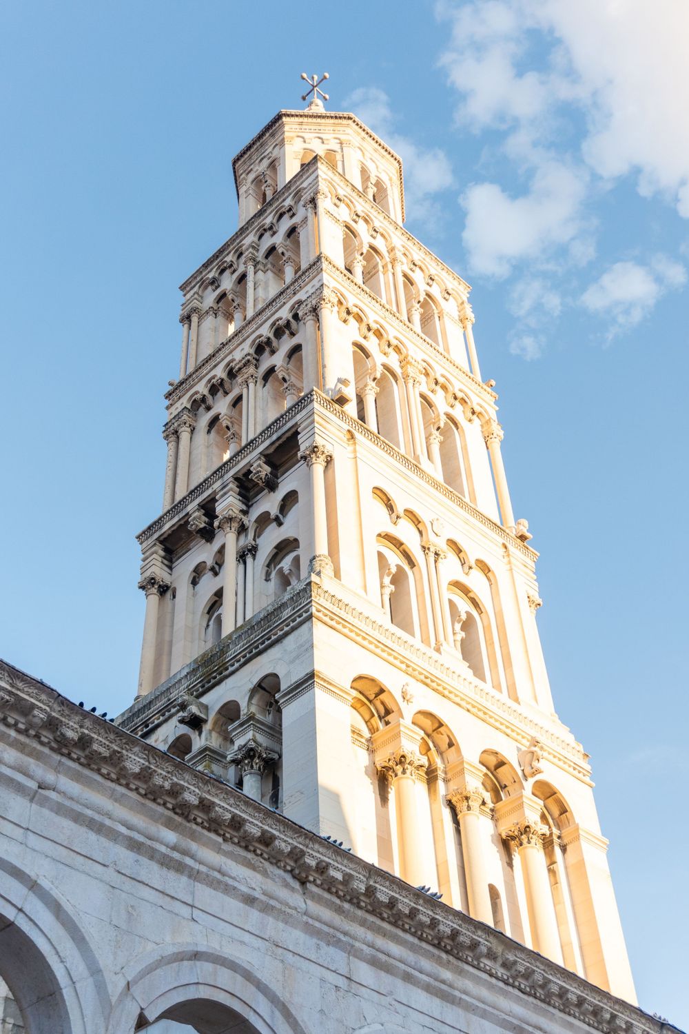White limestone bell tower of Split's Cathedral of Saint Domnius against blue sky.