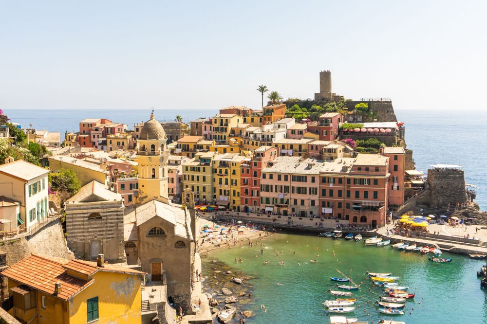 Vernazza harbor in Cinque Terre with colorful buildings cascading down to turquoise bay.