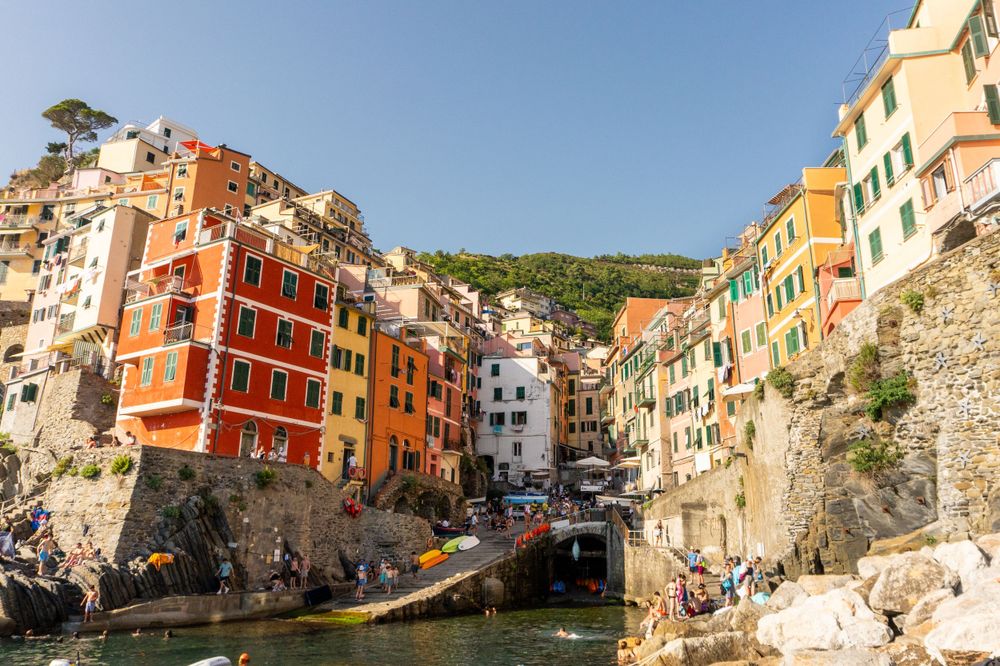 Steep cliffside village of Riomaggiore with vibrant buildings overlooking small harbor.