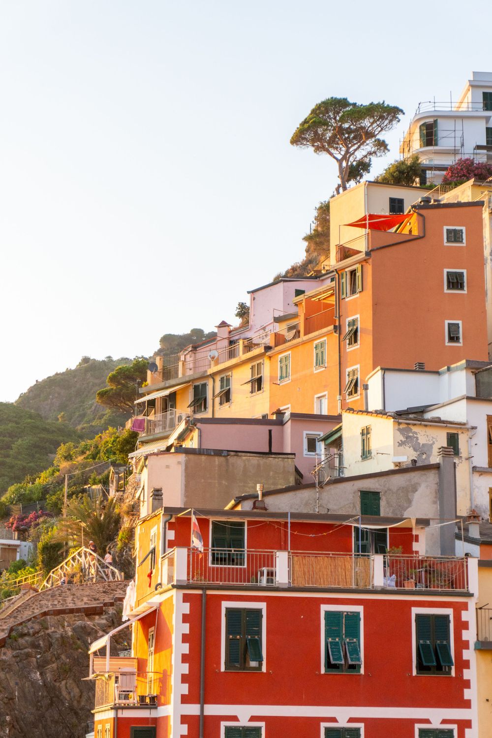 Terraced orange and yellow buildings climbing hillside in Cinque Terre with stone architecture.