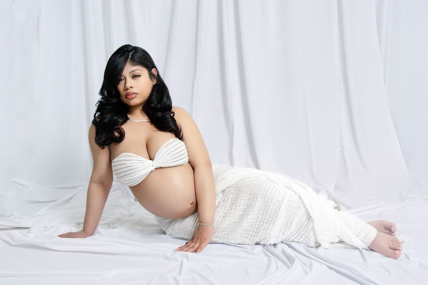 Artistic maternity portraits with gentle poses and soft white drapery.