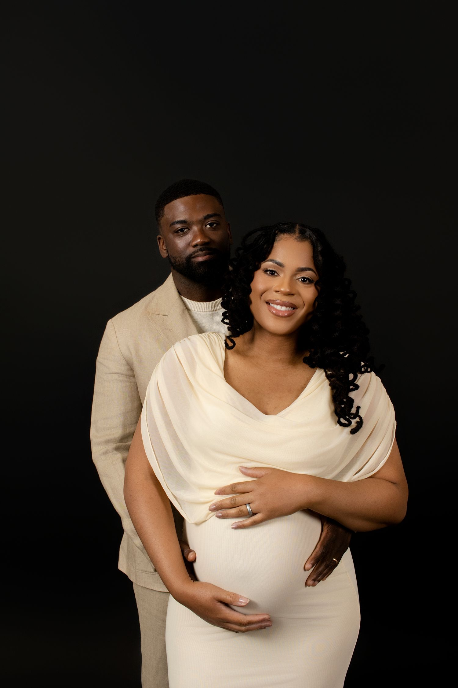 Artistic maternity photoshoot featuring couple in coordinated cream and white outfits.