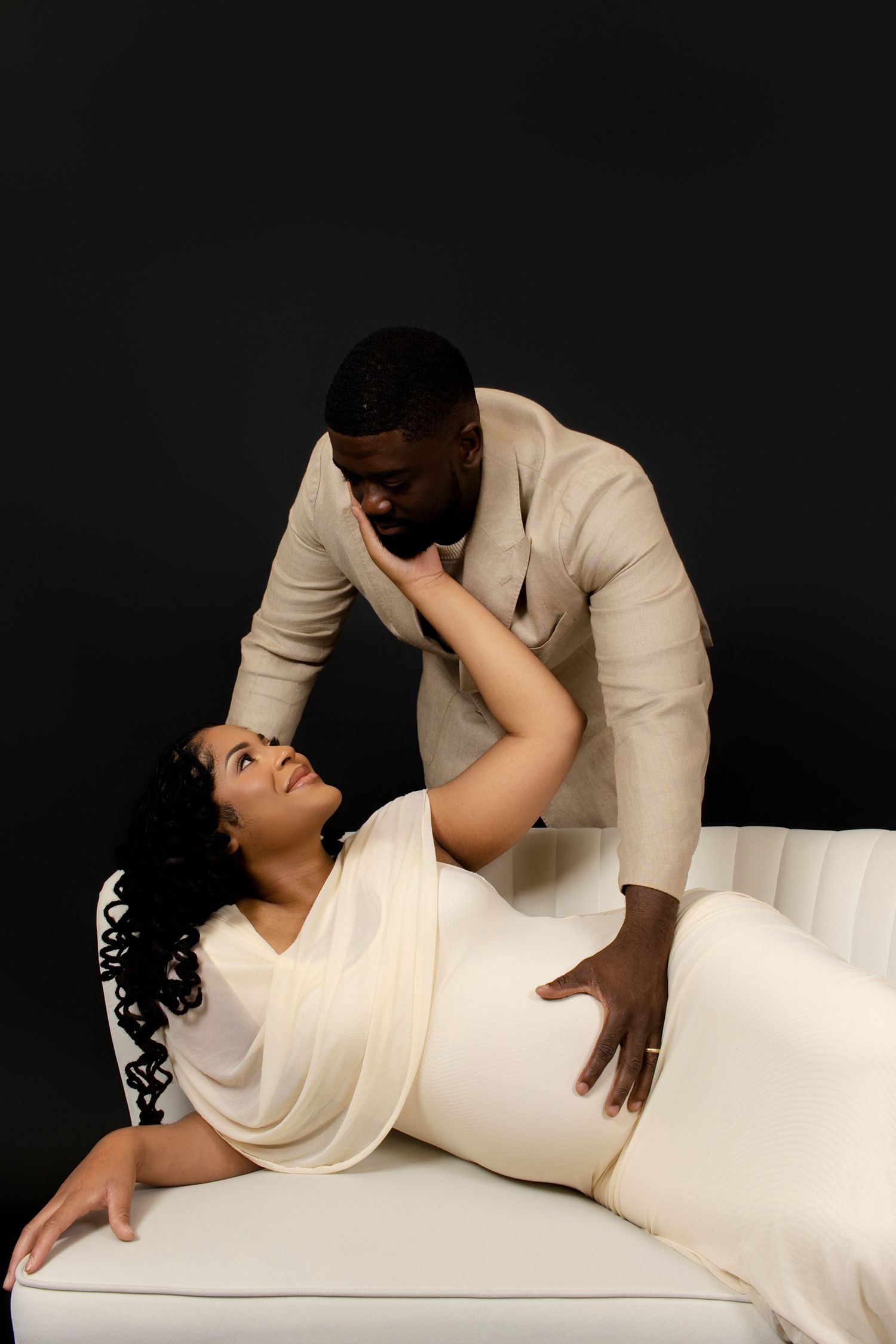 Dramatic maternity poses on white surface against black background.