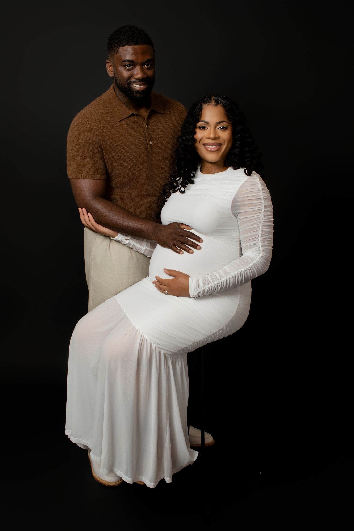 Maternity photography session with couple in brown and white clothing.