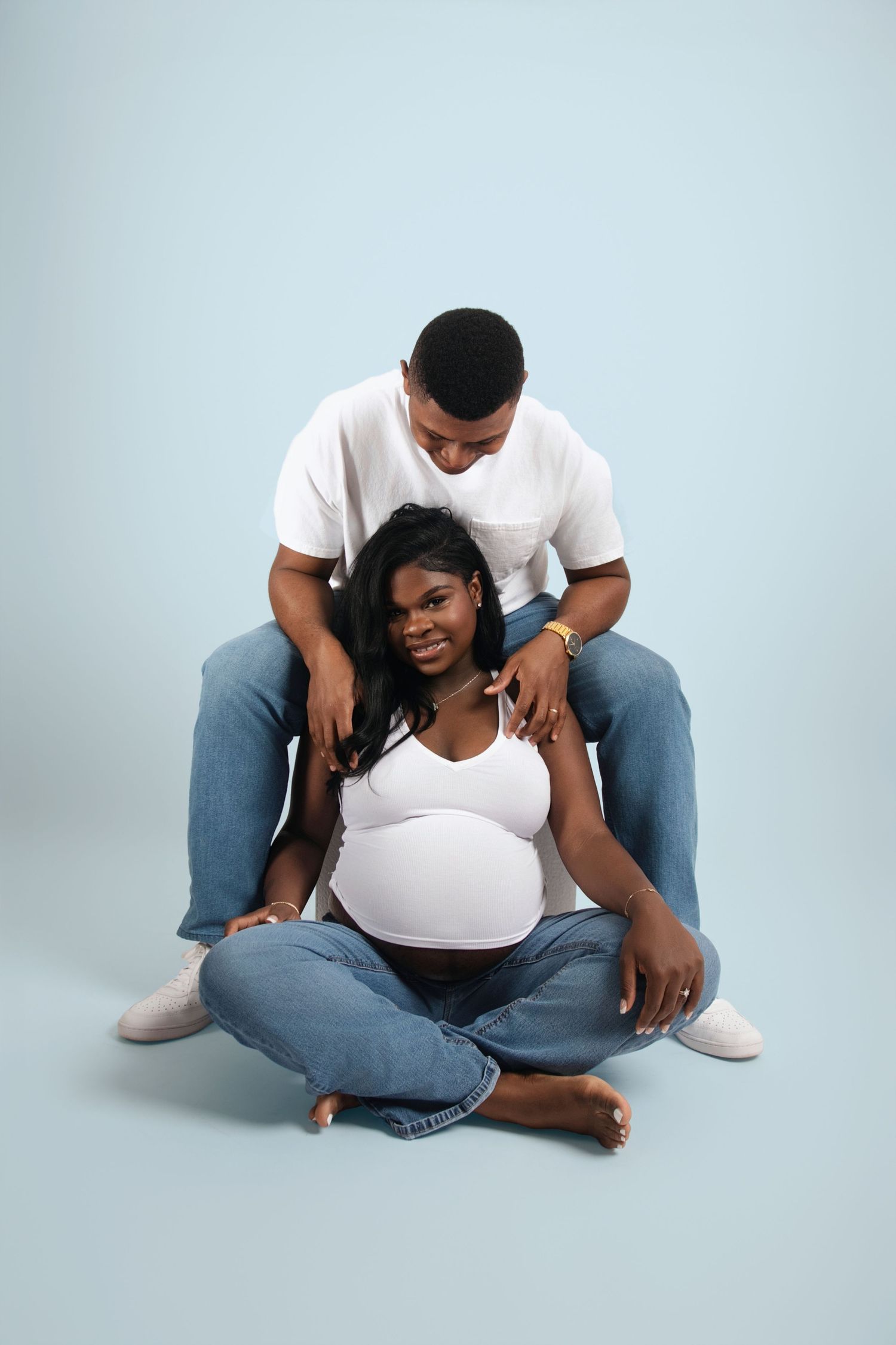 Casual lifestyle photoshoot with two people in white shirts and jeans on light blue background.