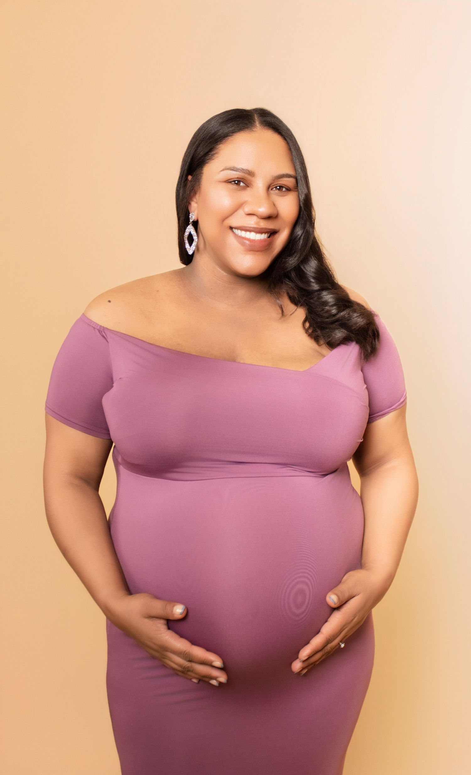 A woman in a pink dress shows her pregnancy in a series of joyful maternity portraits.