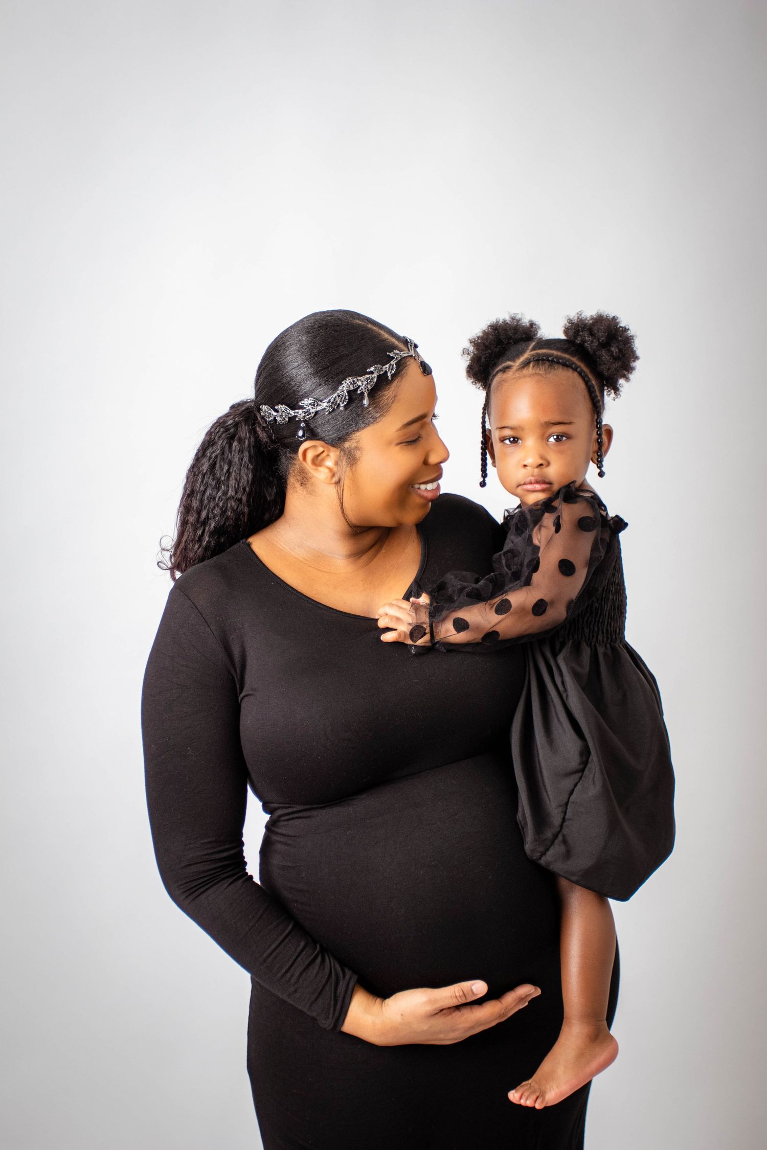 Sweet family portrait session in black outfits against white studio background.