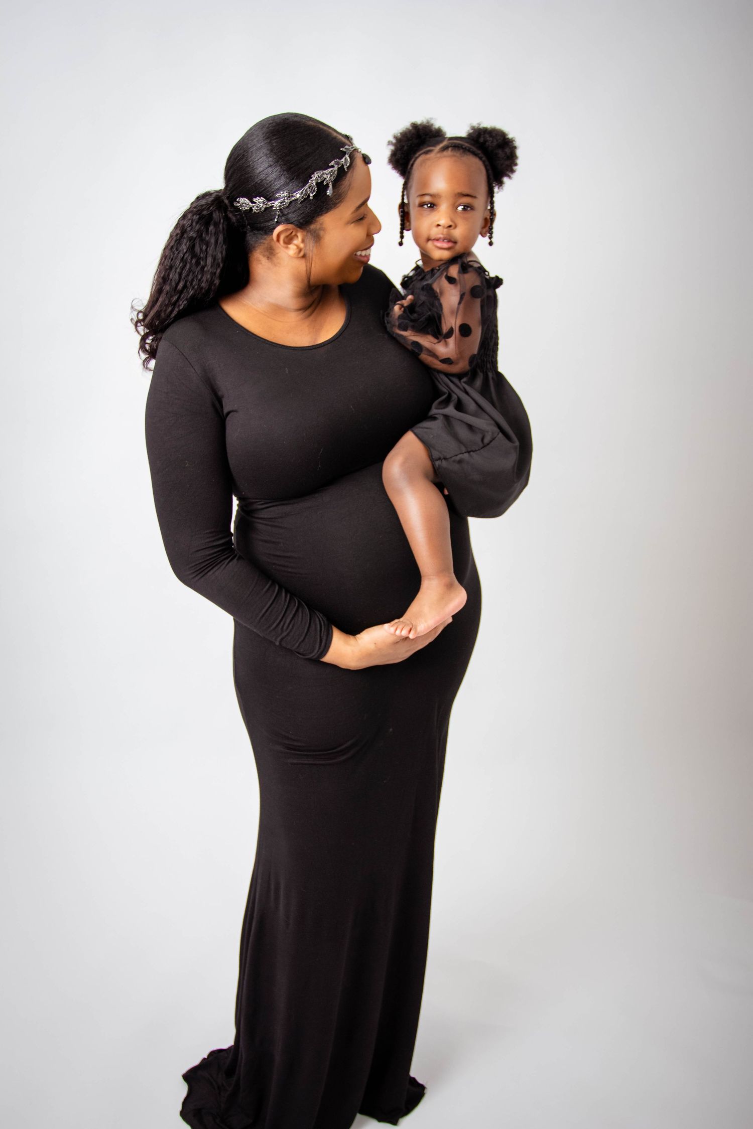 Candid family moments captured in black attire against white backdrop.